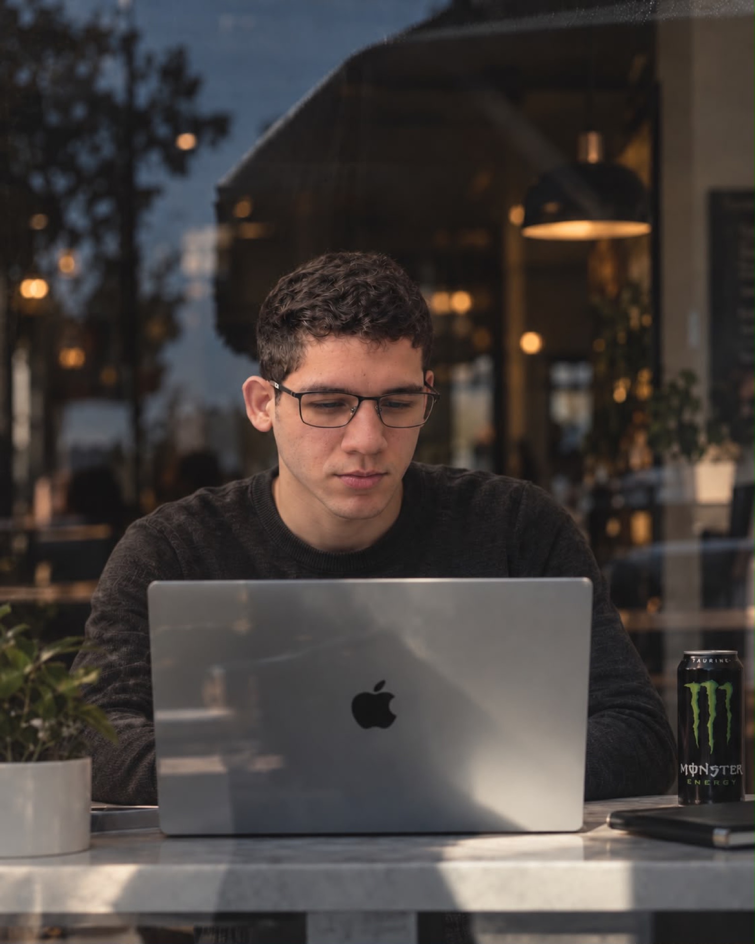 Guilherme trabalhando em seu notebook em uma cafeteria.